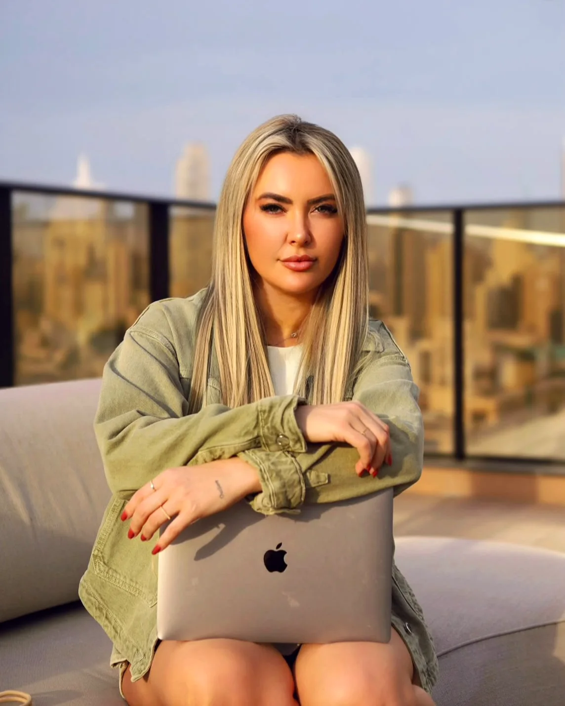 Graziele Dalpra abraçada ao notebook, num terraço no fim de tarde
